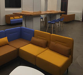 Colored sofas and design stools to furnish office and study atrium